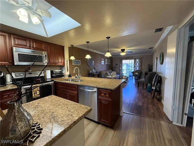 kitchen featuring crown molding, ceiling fan, a peninsula, appliances with stainless steel finishes, and a sink