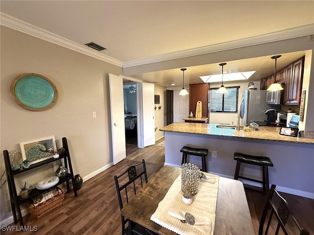 dining room featuring visible vents, baseboards, ornamental molding, dark wood finished floors, and a skylight