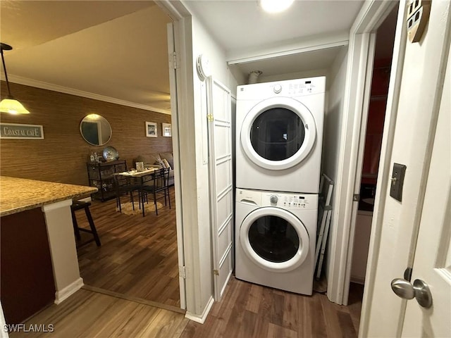 laundry area featuring stacked washer / drying machine, laundry area, and wood finished floors