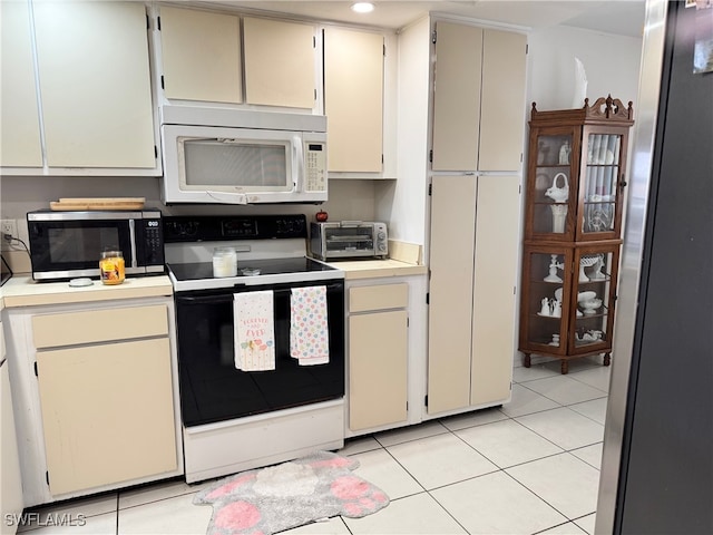 kitchen featuring stainless steel microwave, light tile patterned floors, a toaster, electric range oven, and white microwave