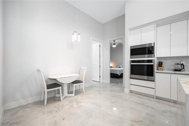 302 NW 1st St, Cape Coral, FL 33993 - dining area featuring light marble finish flooring, a ceiling fan, baseboards, and a high ceiling