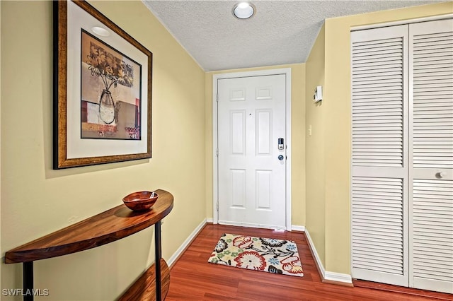 doorway featuring baseboards, a textured ceiling, and wood finished floors