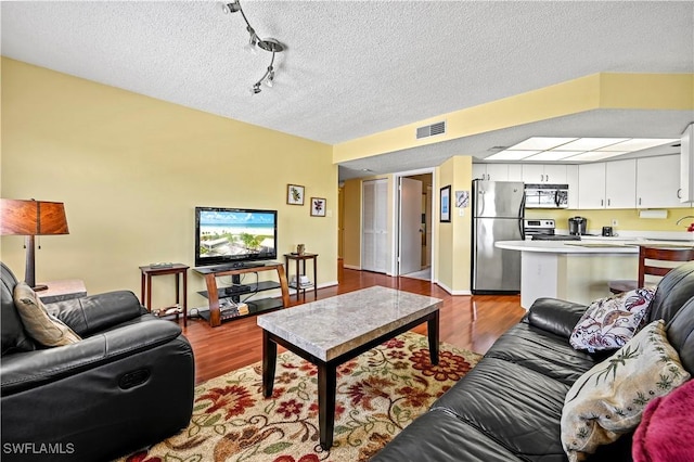 living area featuring a textured ceiling, wood finished floors, and visible vents