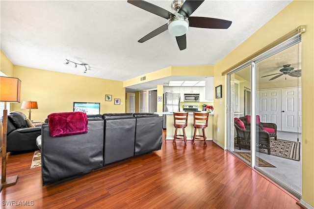 living area with visible vents, a ceiling fan, a textured ceiling, and dark wood-style floors