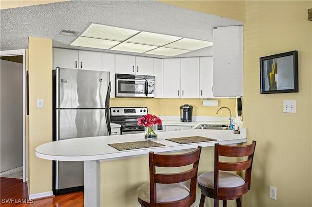 kitchen with a sink, appliances with stainless steel finishes, a peninsula, and light countertops