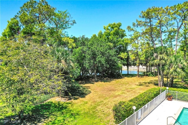 view of yard with a water view, fence, and a fenced in pool
