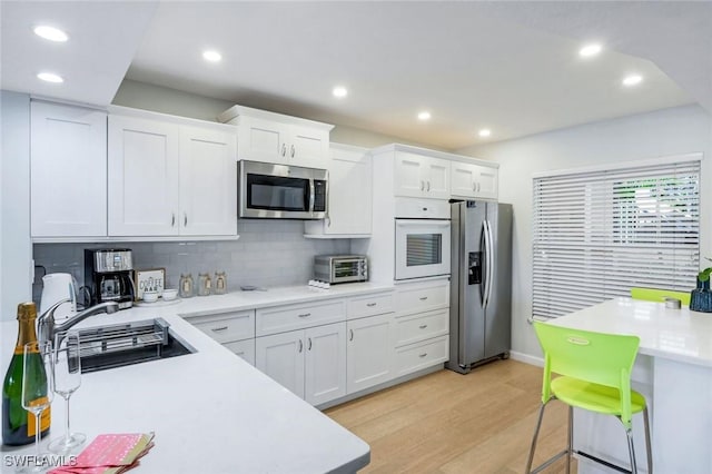 kitchen featuring light countertops, light wood-style flooring, stainless steel appliances, recessed lighting, and white cabinetry