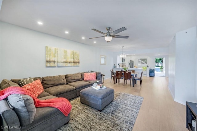 living area with light wood-type flooring, a ceiling fan, baseboards, and recessed lighting