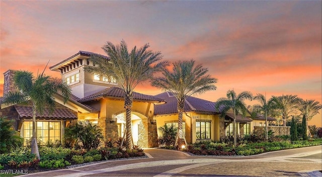 mediterranean / spanish-style home with stucco siding, stone siding, and a tile roof