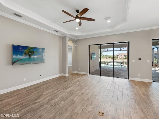 unfurnished living room with visible vents, ceiling fan, light wood-type flooring, and a raised ceiling