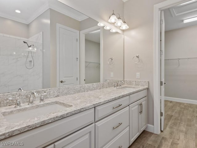 full bath featuring a sink, a spacious closet, tiled shower, and double vanity