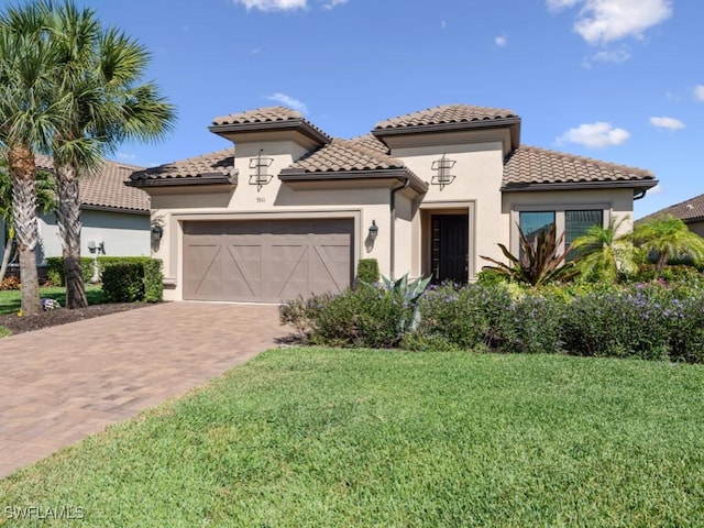 mediterranean / spanish home featuring a tiled roof, an attached garage, decorative driveway, and a front lawn
