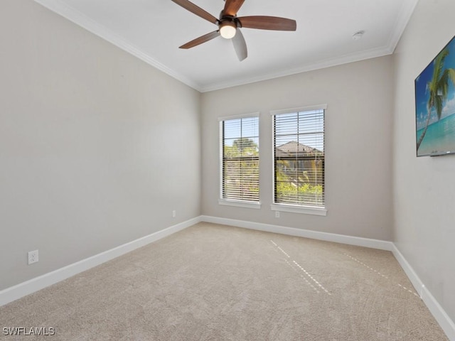 empty room with crown molding, ceiling fan, light colored carpet, and baseboards