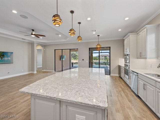kitchen featuring crown molding, a center island, appliances with stainless steel finishes, and light wood-style floors