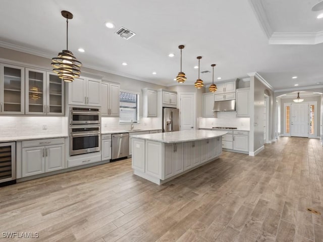 kitchen featuring tasteful backsplash, visible vents, a sink, under cabinet range hood, and stainless steel appliances
