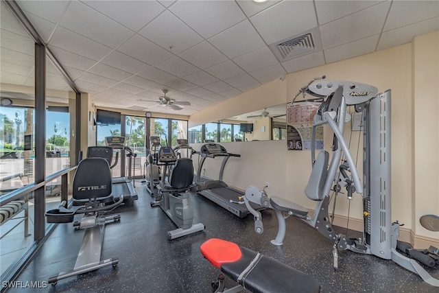 exercise room with a paneled ceiling, visible vents, and a ceiling fan