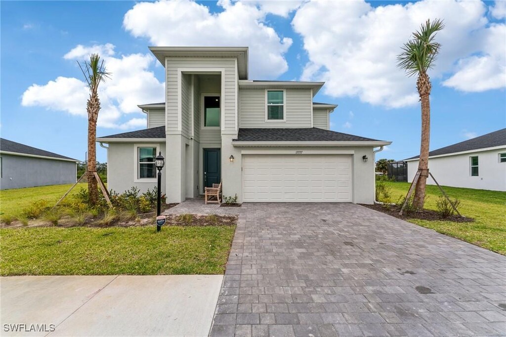 17777 Saddleback Loop, North Fort Myers, FL 33917 - view of front facade with a front lawn, a shingled roof, an attached garage, and decorative driveway