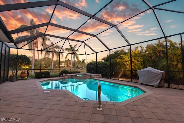 pool at dusk with a patio area, a lanai, a pool with connected hot tub, and area for grilling