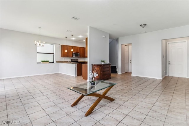 unfurnished living room featuring a chandelier, light tile patterned floors, visible vents, and baseboards