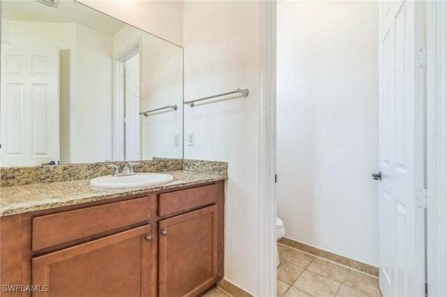 bathroom with toilet, vanity, and tile patterned flooring