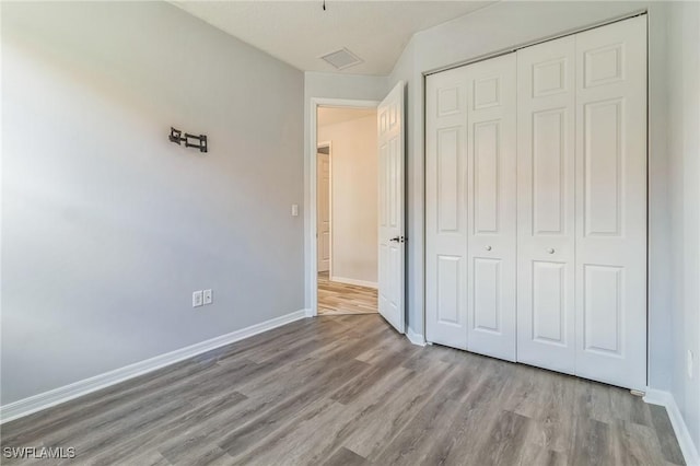 unfurnished bedroom featuring a closet, baseboards, and wood finished floors