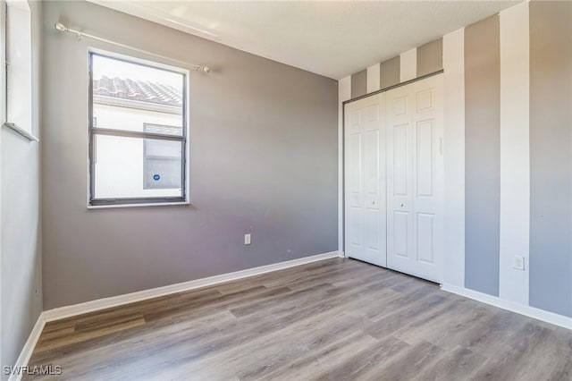 unfurnished bedroom with a closet, baseboards, and wood finished floors