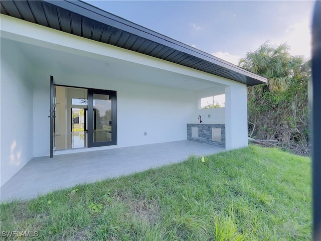 856 Jaguar Blvd, Lehigh Acres, FL 33974 - rear view of property featuring stucco siding, a sink, and a patio area