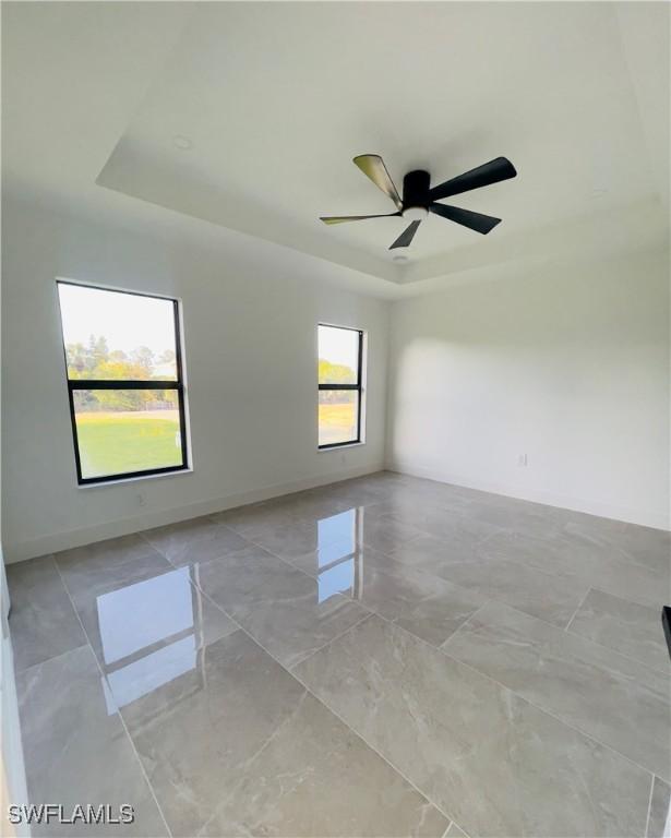 856 Jaguar Blvd, Lehigh Acres, FL 33974 - empty room with baseboards, a tray ceiling, and a ceiling fan