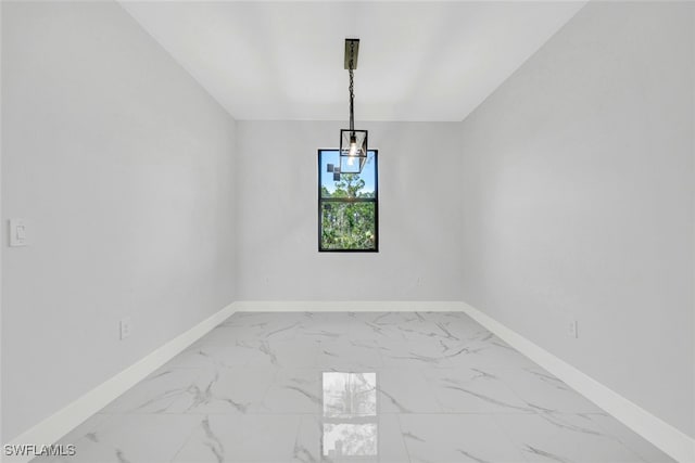 empty room featuring marble finish floor and baseboards