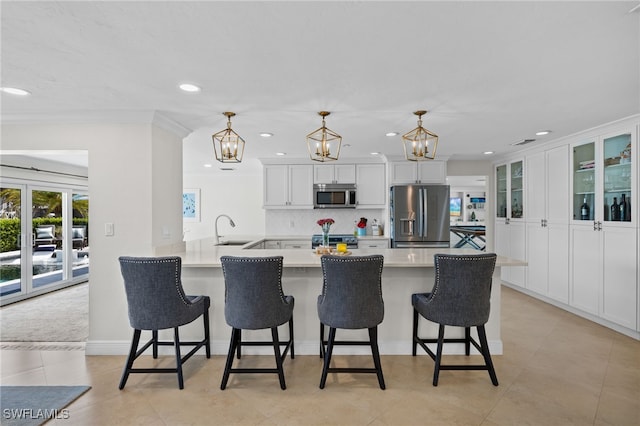kitchen featuring a peninsula, stainless steel appliances, tasteful backsplash, a sink, and a breakfast bar area