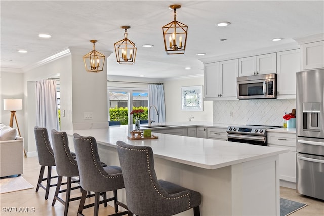 kitchen with crown molding, an inviting chandelier, a sink, a peninsula, and appliances with stainless steel finishes