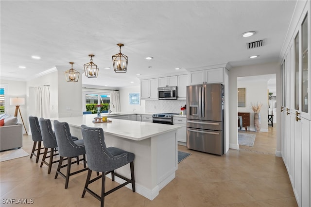 kitchen with a kitchen breakfast bar, appliances with stainless steel finishes, a peninsula, visible vents, and decorative backsplash
