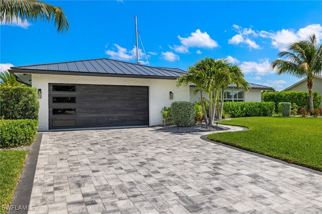 view of front of property with metal roof, decorative driveway, a garage, a front yard, and a standing seam roof