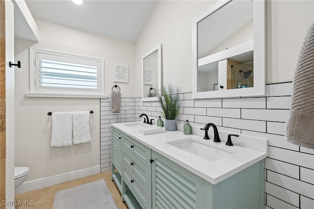 bathroom with double vanity, a tile shower, lofted ceiling, and a sink