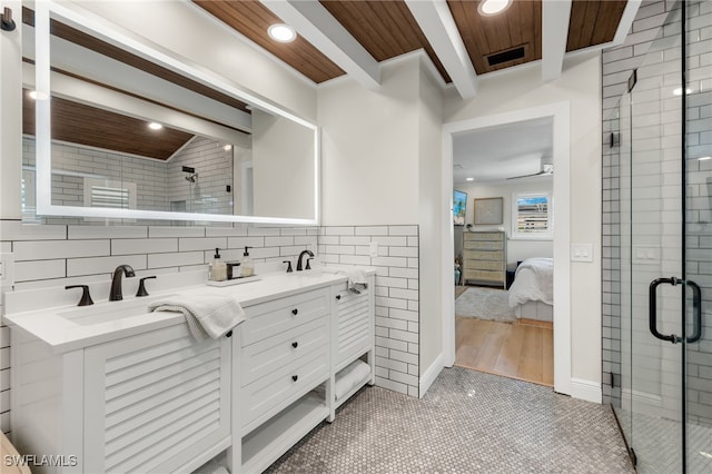 ensuite bathroom featuring beam ceiling, a sink, a shower stall, ensuite bath, and tile walls