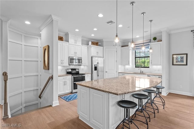 kitchen with a sink, visible vents, stainless steel appliances, a center island, and light wood-type flooring