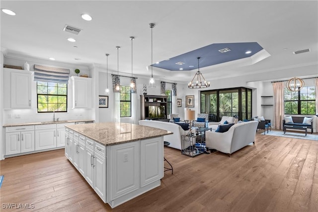 8756 Bellano Ct Unit 201, Naples, FL 34119 - kitchen with open floor plan, a chandelier, ornamental molding, a sink, and a center island