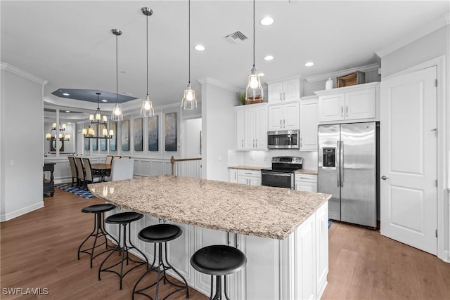 8756 Bellano Ct Unit 201, Naples, FL 34119 - kitchen with appliances with stainless steel finishes, ornamental molding, wood finished floors, a kitchen island, and a chandelier