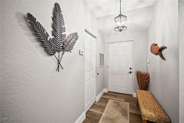 4665 Saint Croix Ln Unit 1525, Naples, FL 34109 - doorway to outside with baseboards, wood finished floors, a textured wall, and a chandelier