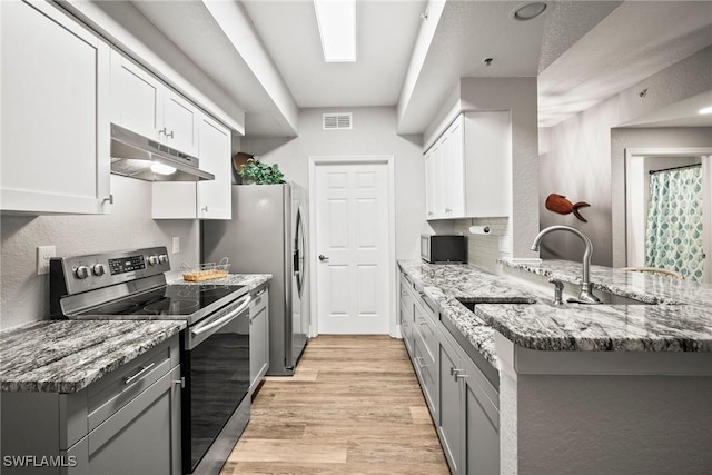 4665 Saint Croix Ln Unit 1525, Naples, FL 34109 - kitchen featuring light stone counters, stainless steel range with electric stovetop, a peninsula, light wood-type flooring, and under cabinet range hood