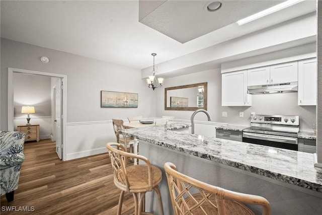 4665 Saint Croix Ln Unit 1525, Naples, FL 34109 - kitchen with light stone counters, stainless steel range with electric cooktop, a breakfast bar area, under cabinet range hood, and dark wood-style flooring