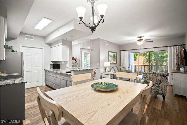 4665 Saint Croix Ln Unit 1525, Naples, FL 34109 - dining room featuring ceiling fan with notable chandelier, visible vents, and light wood-type flooring