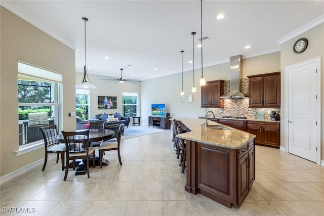 9337 Campanile Cir, Naples, FL 34114 - kitchen with crown molding, tasteful backsplash, a sink, open floor plan, and wall chimney range hood