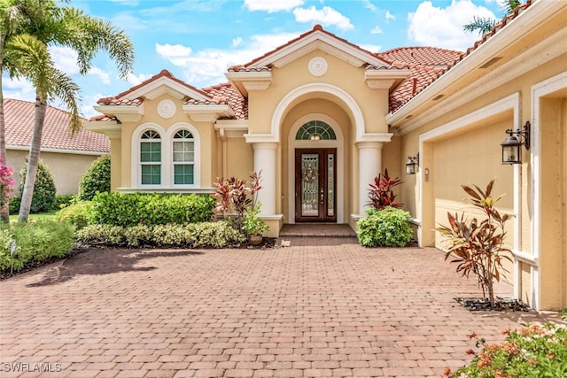 9337 Campanile Cir, Naples, FL 34114 - entrance to property featuring a tiled roof, decorative driveway, stucco siding, and an attached garage