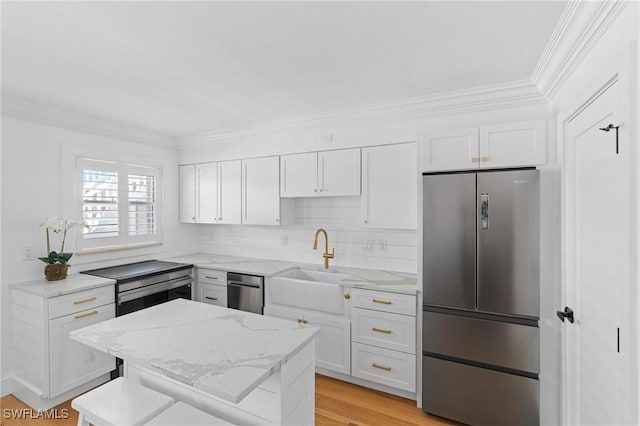 980 7th Ave S Unit 107, Naples, FL 34102 - kitchen with appliances with stainless steel finishes, crown molding, white cabinetry, and light stone counters