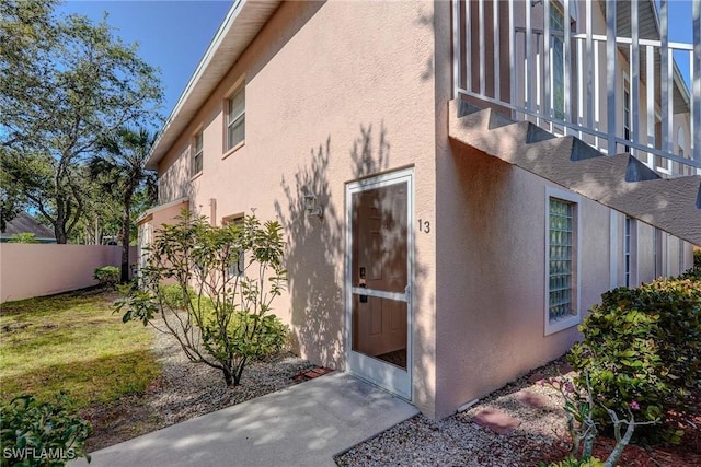 view of side of property featuring fence and stucco siding