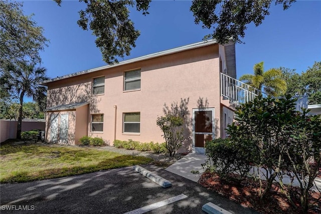 exterior space with stucco siding, a yard, and uncovered parking