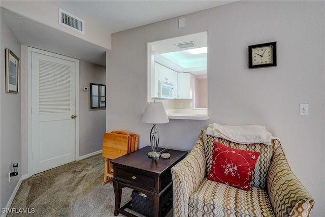 living area with baseboards, visible vents, and carpet floors