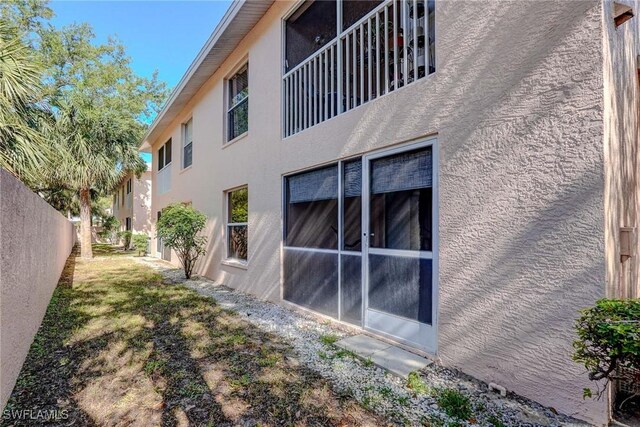view of property exterior with stucco siding and fence