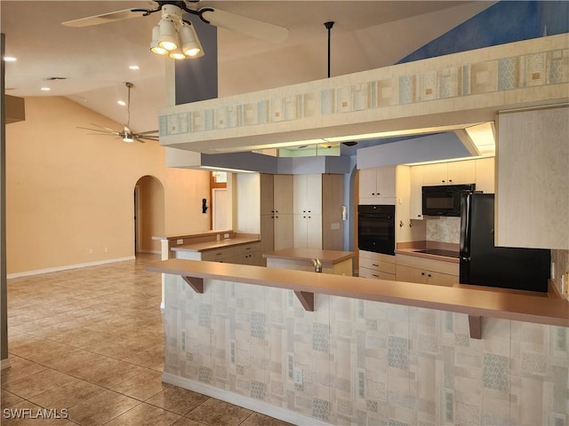 kitchen with arched walkways, ceiling fan, black appliances, and light tile patterned floors